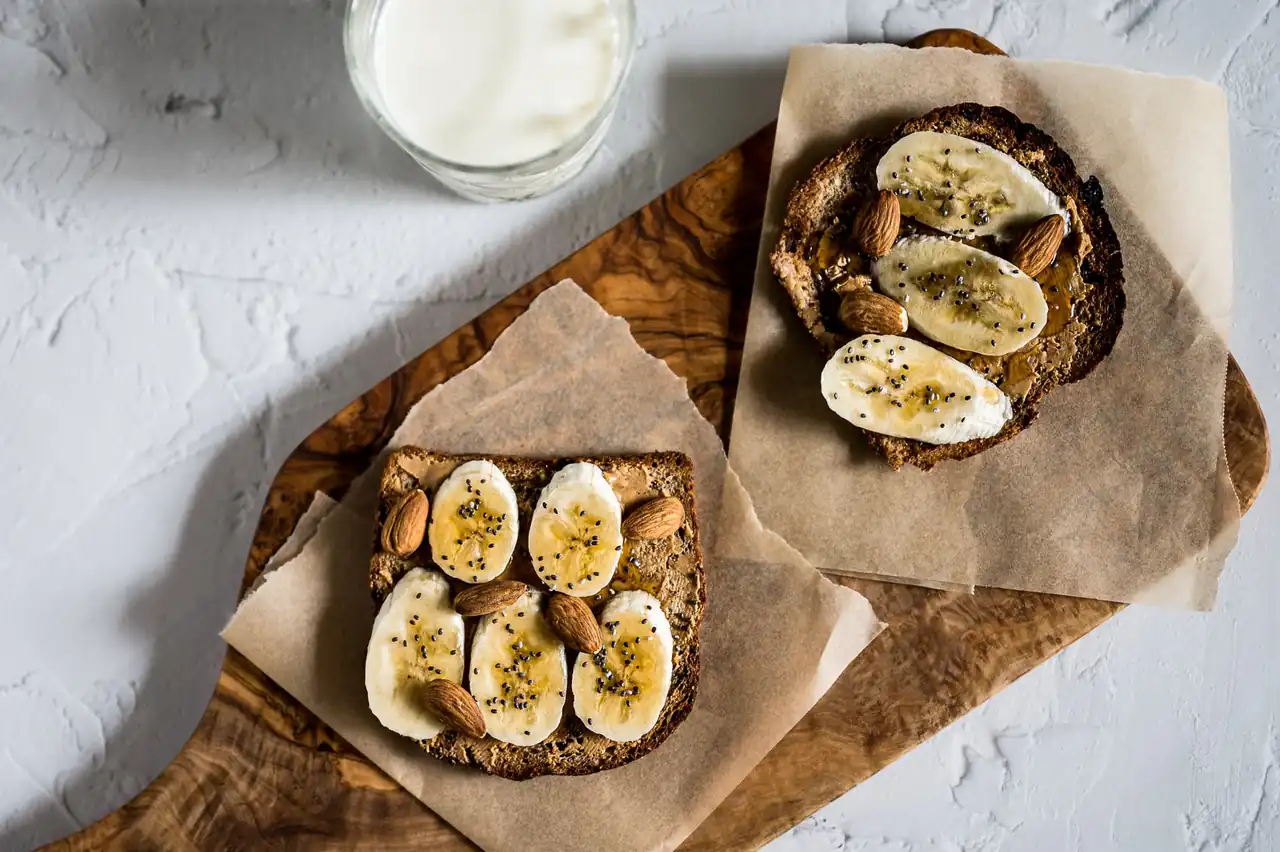 Desayuno saludable con plátano, tostadas y yogur para ilustrar que comer antes de hacer deporte.
