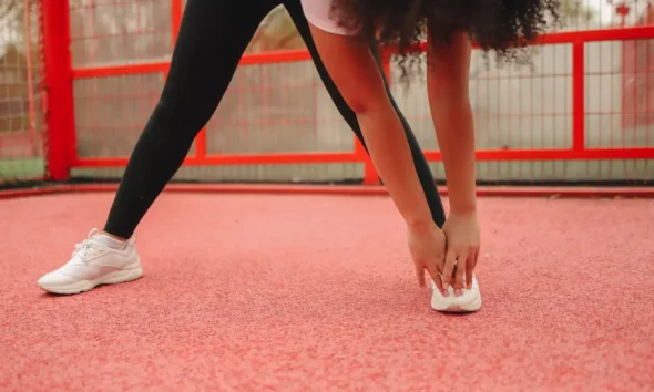 Corredor estirando las piernas después de entrenar, ilustrando es buena señal tener agujetas después de hacer ejercicio.
